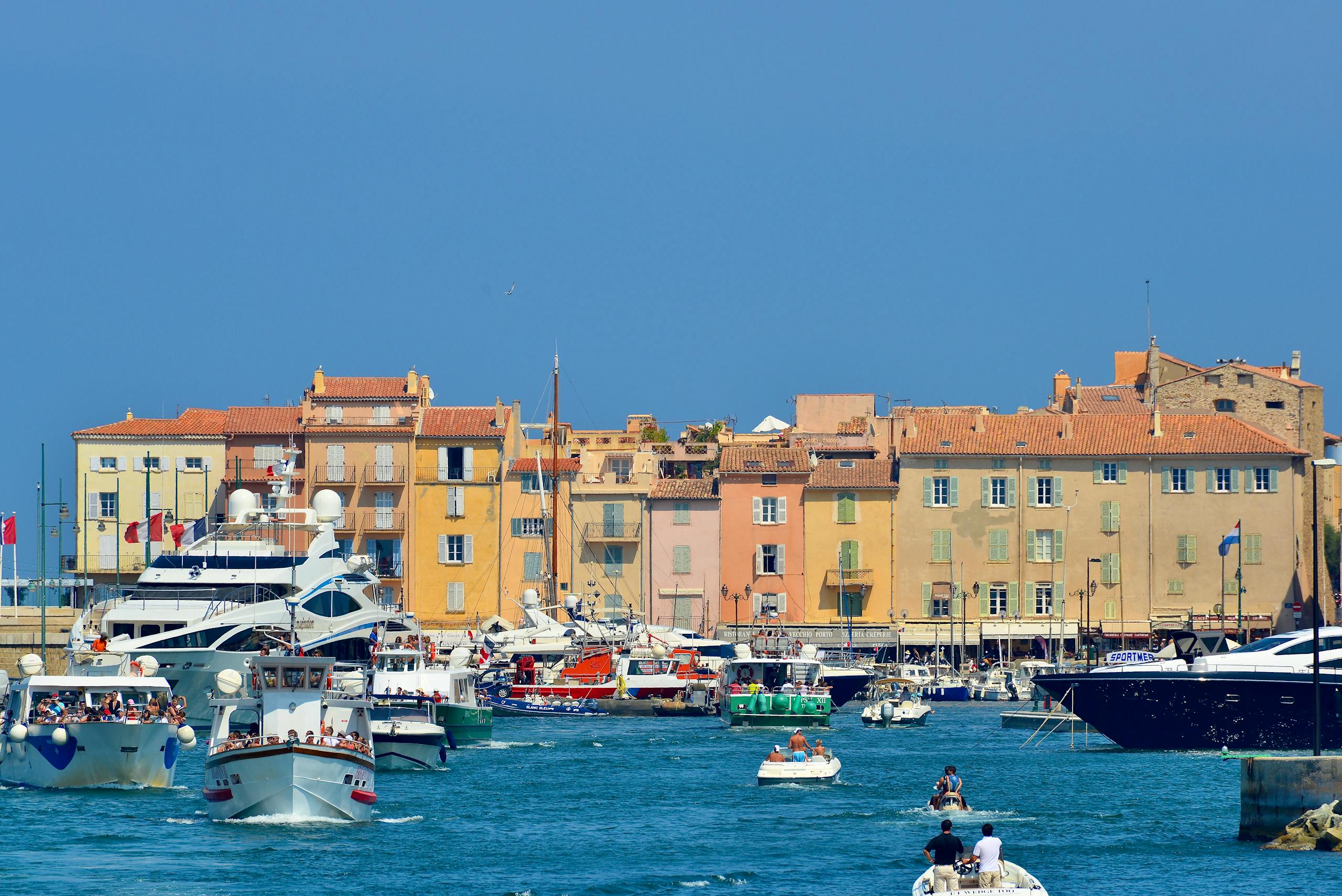Elegant yachts in the bustling harbor of Saint-Tropez under a clear blue sky.